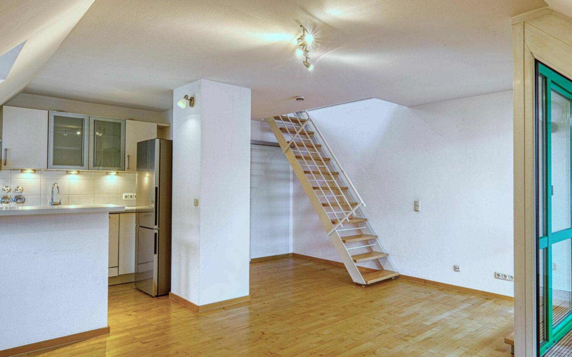 Offener Wohnbereich mit Küchenzeile, Holztreppe und Parkettboden in einer Wohnung in Thalkirchen.