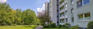 Panoramaansicht eines Wohnhauses mit begrüntem Vorplatz, Bäumen und Weg in Unterhaching.