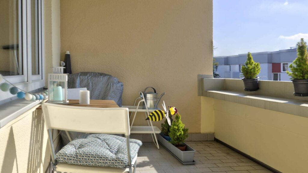 Balcony with seating, plants, and a view of neighboring houses in Munich-Untermenzing.