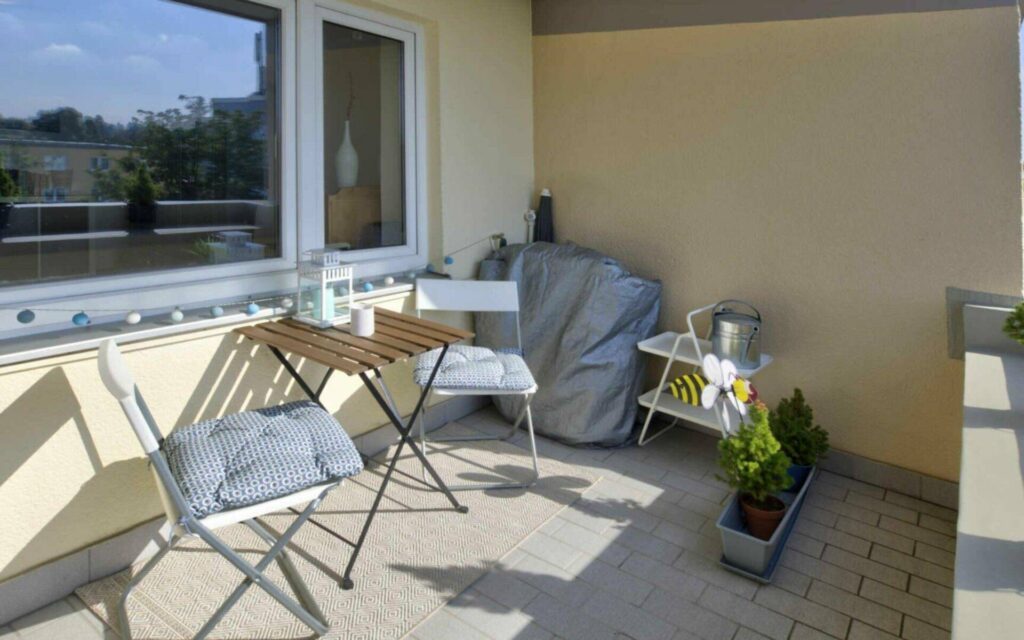 Cozy balcony with a table, chairs, and plants, as well as a green view in Munich-Untermenzing.