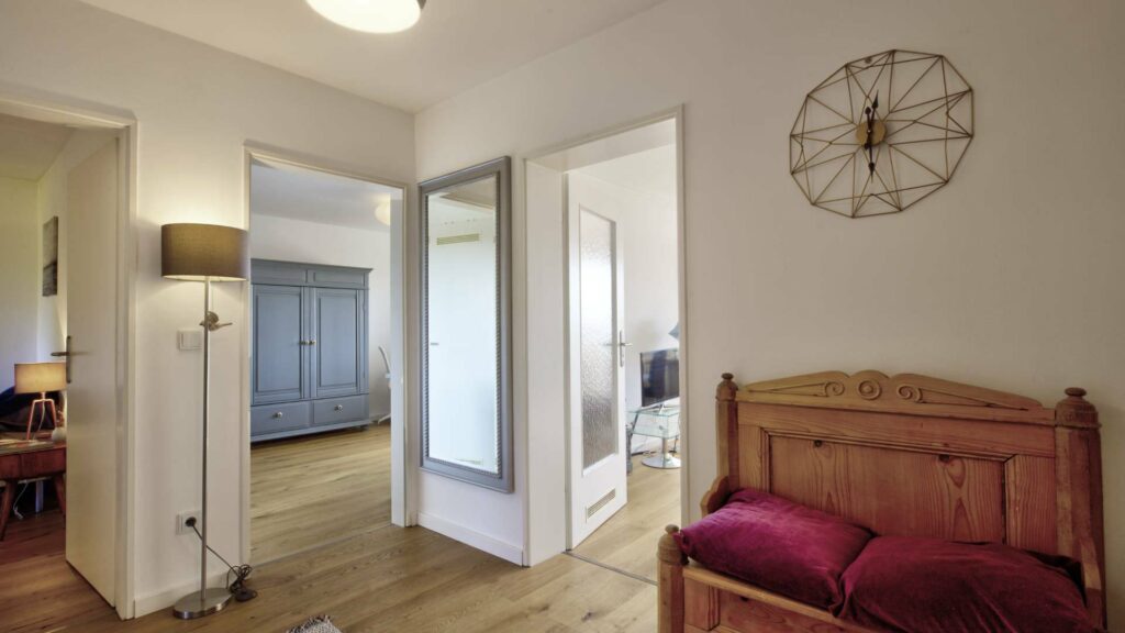 Inhabited hallway with wall clock, wooden bench and view into other rooms of an apartment in Untermenzing.