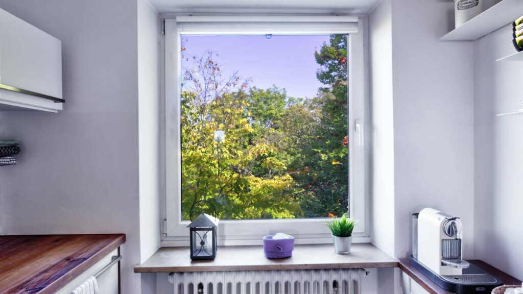Kitchen window with a view of autumn trees, decoration, and coffee maker in an apartment in Untermenzing.