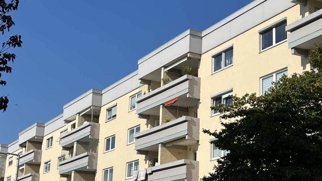 Facade of an apartment building with bright balconies under a blue sky in Munich-Untermenzing.