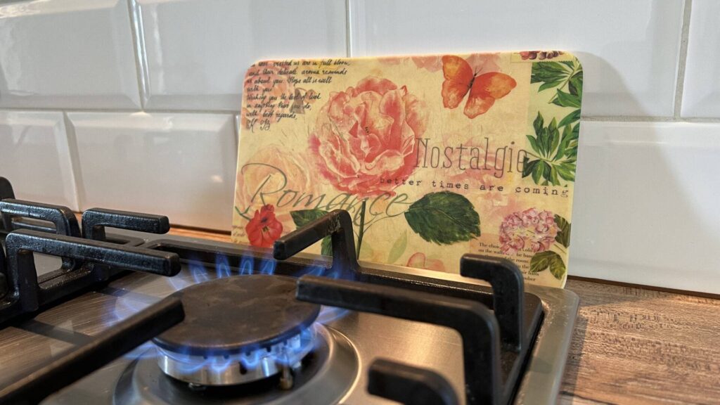 Gas stove with burning flame and decorative cutting board in a kitchen in Untermenzing.