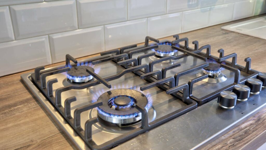 Close-up of a gas stove with burning flames on a stainless steel cooktop in an eat-in kitchen in Munich-Untermenzing