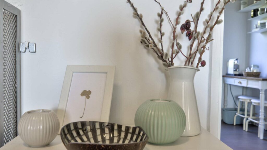 Console table with ceramic vases, willow branches, and bowl, view into the kitchen of an apartment in Munich-Untermenzing – Rogers Immobilien