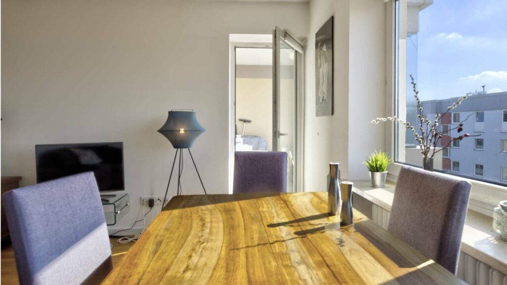 Bright dining area with wooden table, upholstered chairs, and a window with a wide view in Untermenzing.