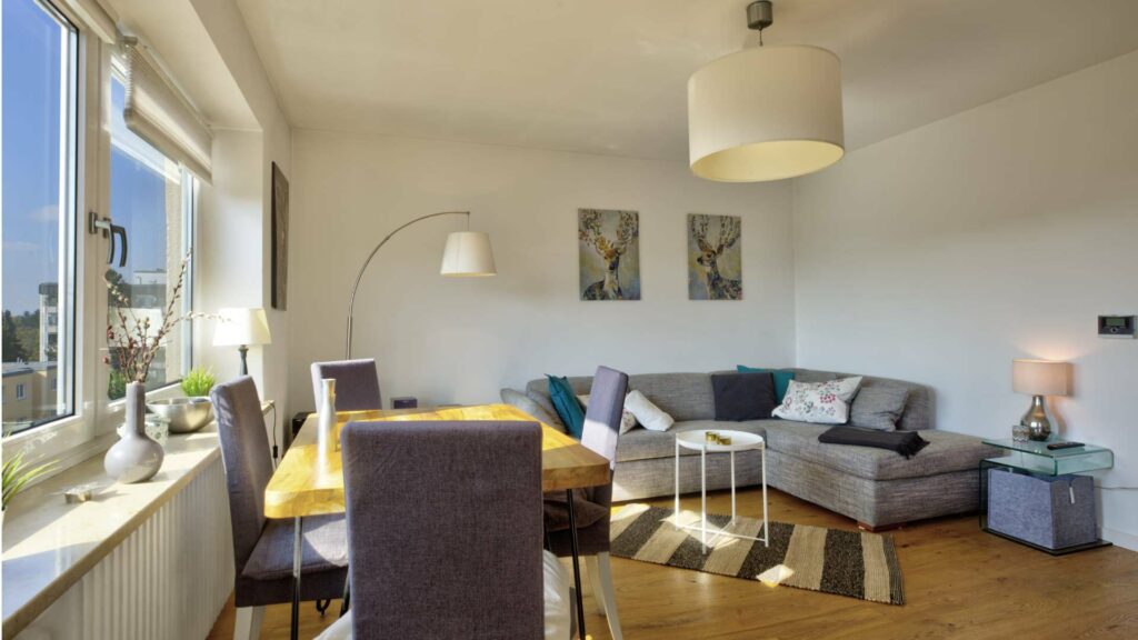 Lived-in living room with a gray couch, dining table, and large window with a view in Untermenzing.