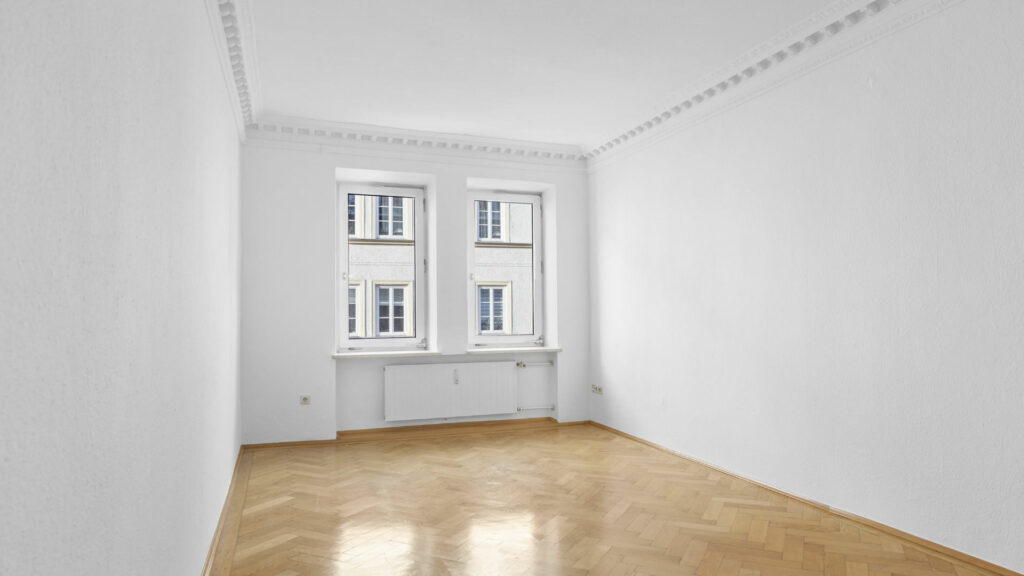 Leerer weißer Raum mit Fenstern und Parkettboden – Symbolbild zur Wohnflächenberechnung bei Immobilien