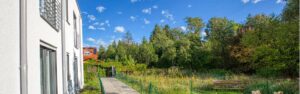 Paved path along the white house facade with views of trees and green spaces in Wolfratshausen