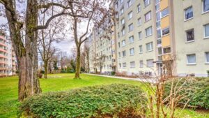 Exterior view of the residential building with a lawn and mature trees in Munich