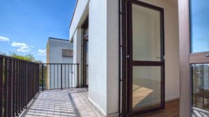 Balkon einer Wohnung in Sendling mit gefliestem Boden, Metallgeländer und Blick auf Nachbargebäude.