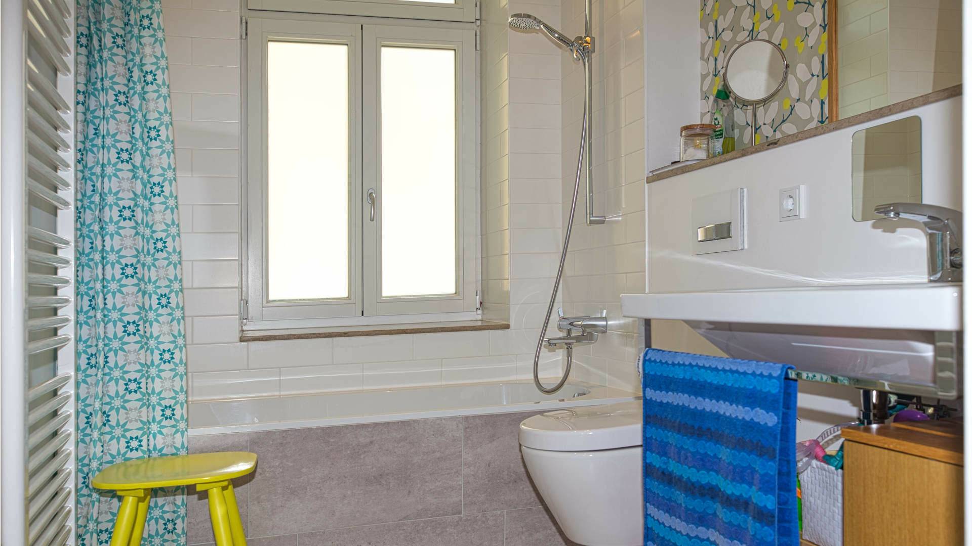 Bathroom of the old building apartment in Au with shower, toilet, washbasin, and yellow stool