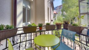 Wrought-iron balcony of the old-style apartment in the Au with colorful furniture, plants, and a view of the city