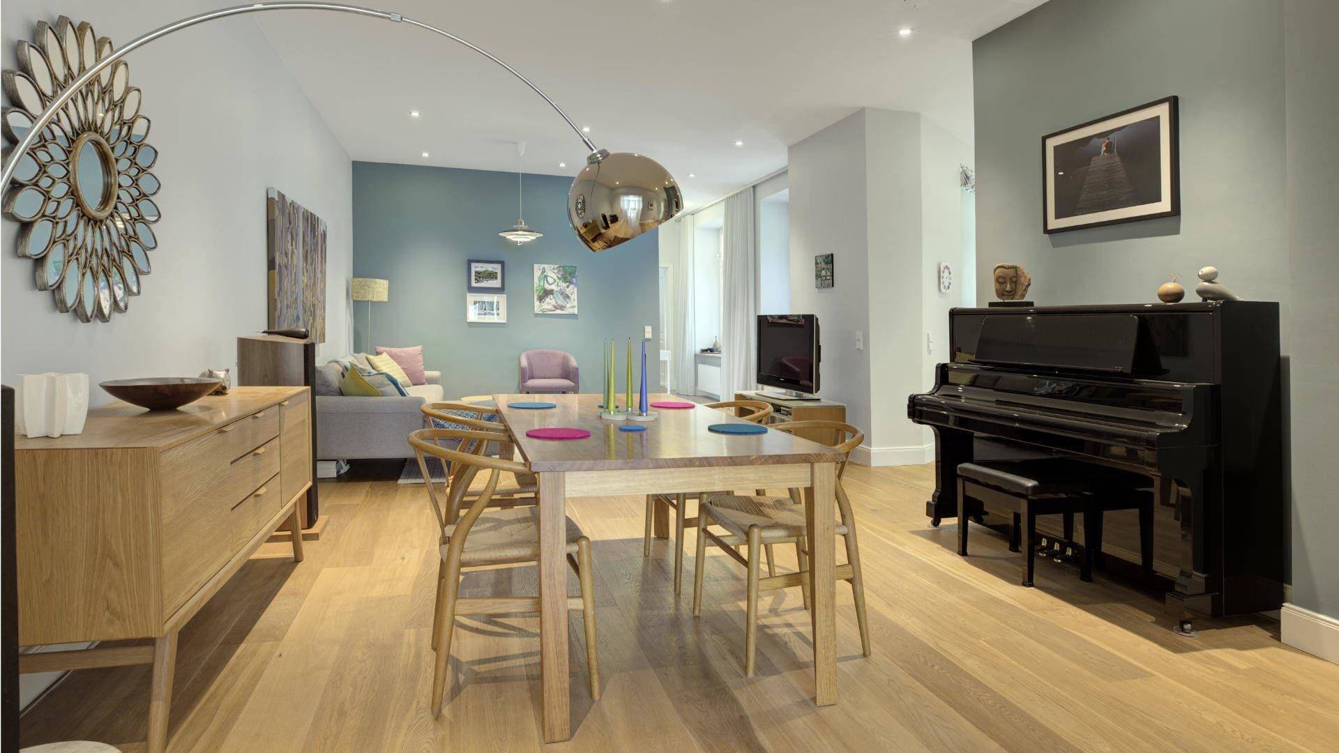 Dining area of a period apartment in the Au district with a dining table, piano, and stylish furnishings.