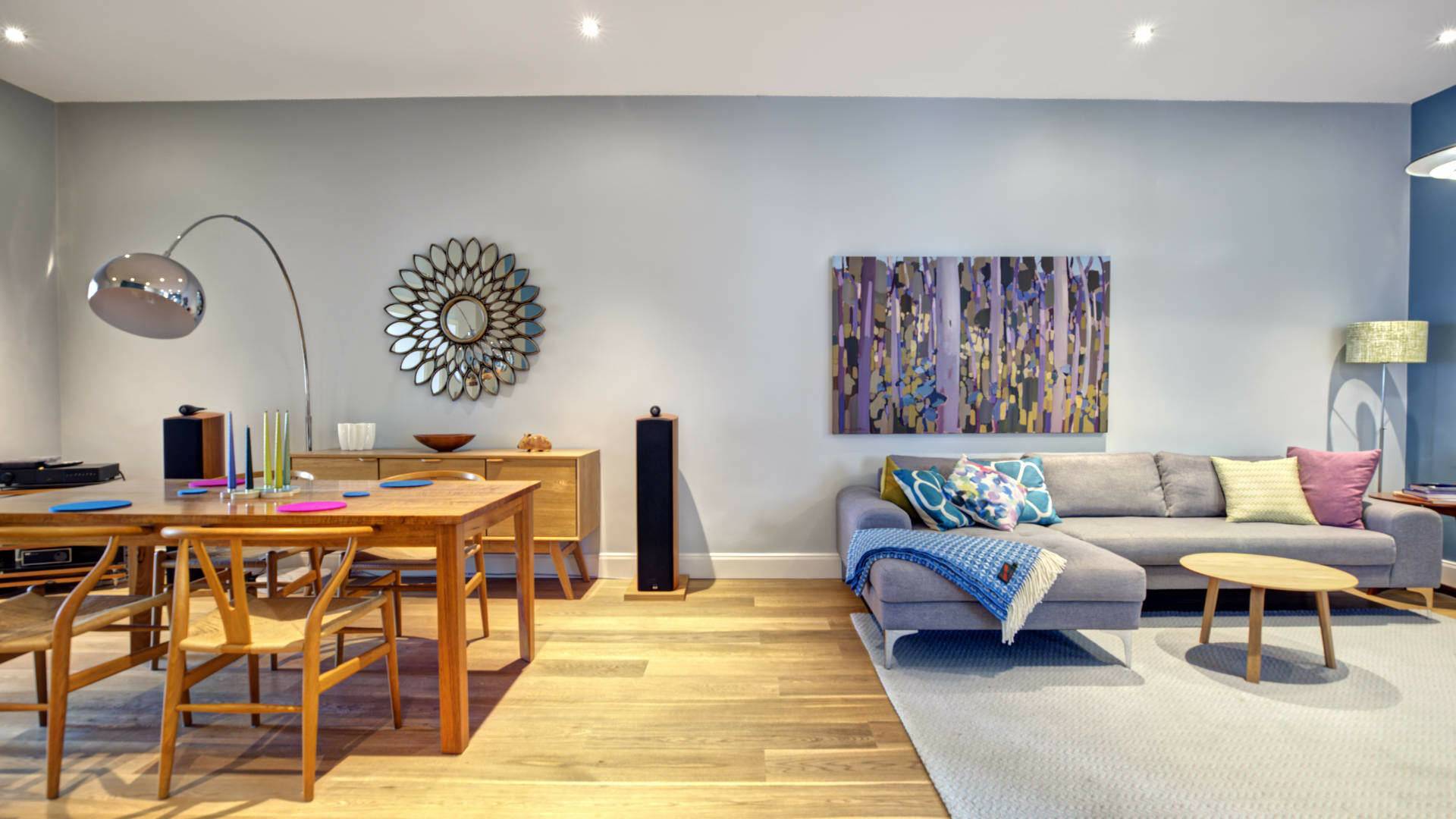 Living and dining area of an old building apartment in the Au district with a dining table, a gray sofa, and art prints on the wall.