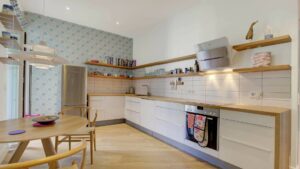 Open kitchen of the old-style apartment in the Au district with white fronts, wooden countertops, and an adjoining dining table