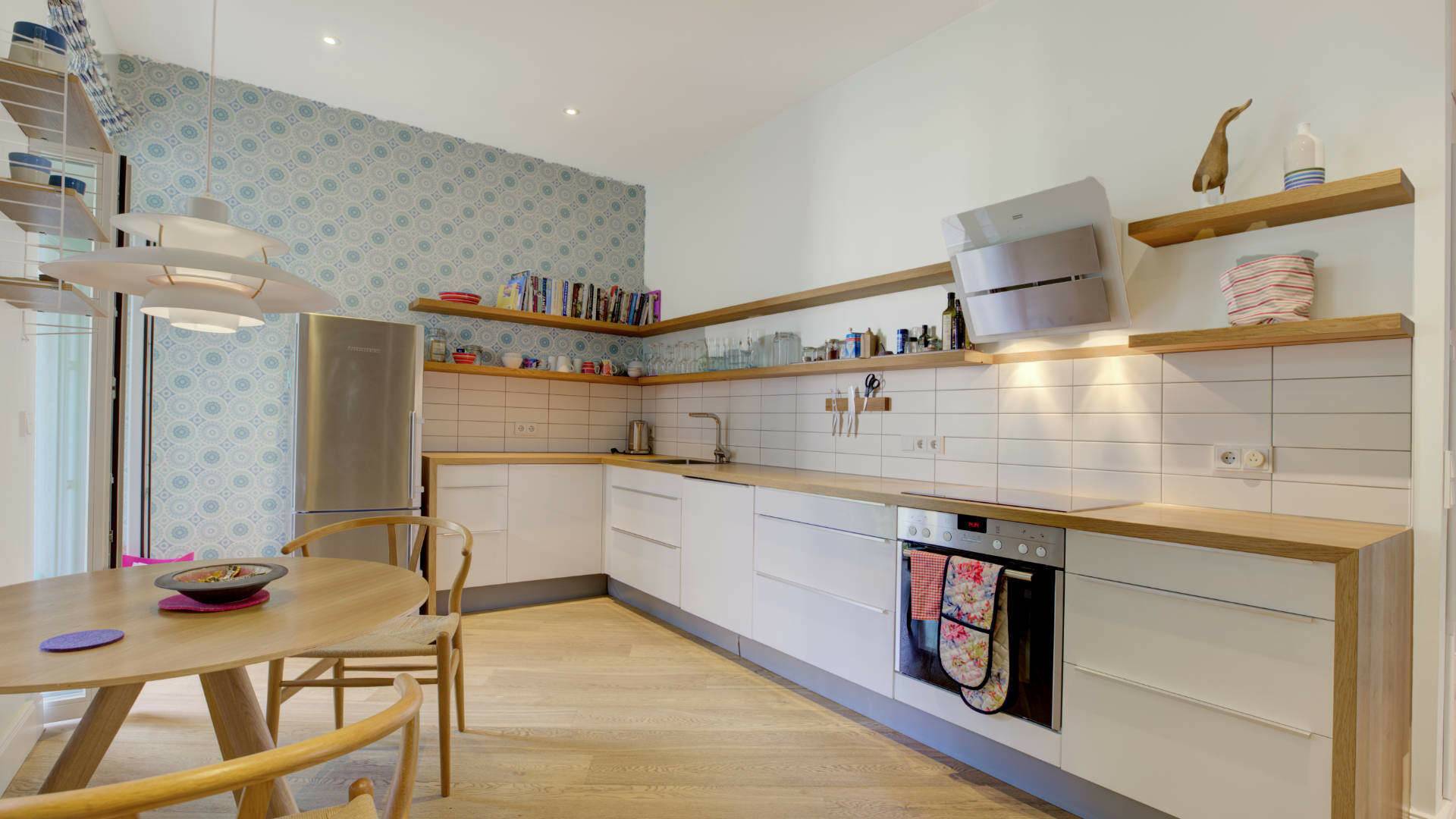 Open kitchen of the old-style apartment in the Au district with white fronts, wooden countertops, and an adjoining dining table