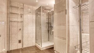 Bathroom in Aubing with walk-in glass shower, heated towel rail and bright tiles.