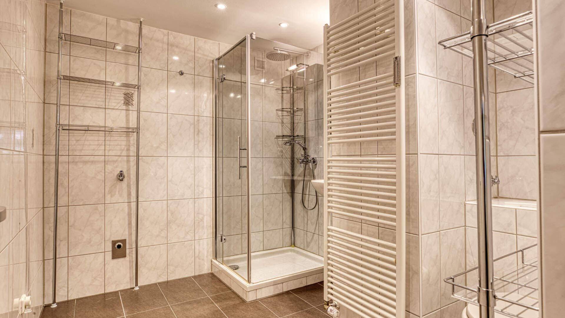 Bathroom in Aubing with walk-in glass shower, heated towel rail and bright tiles.