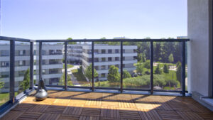 View from the balcony of the new apartment in Aubing over wooden floorboards to the landscaped residential complex