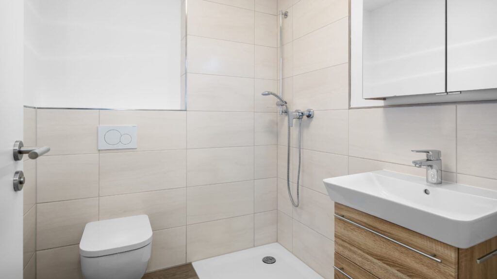 Shower room of the new apartment in Aubing with beige tiles, walk-in shower and washbasin