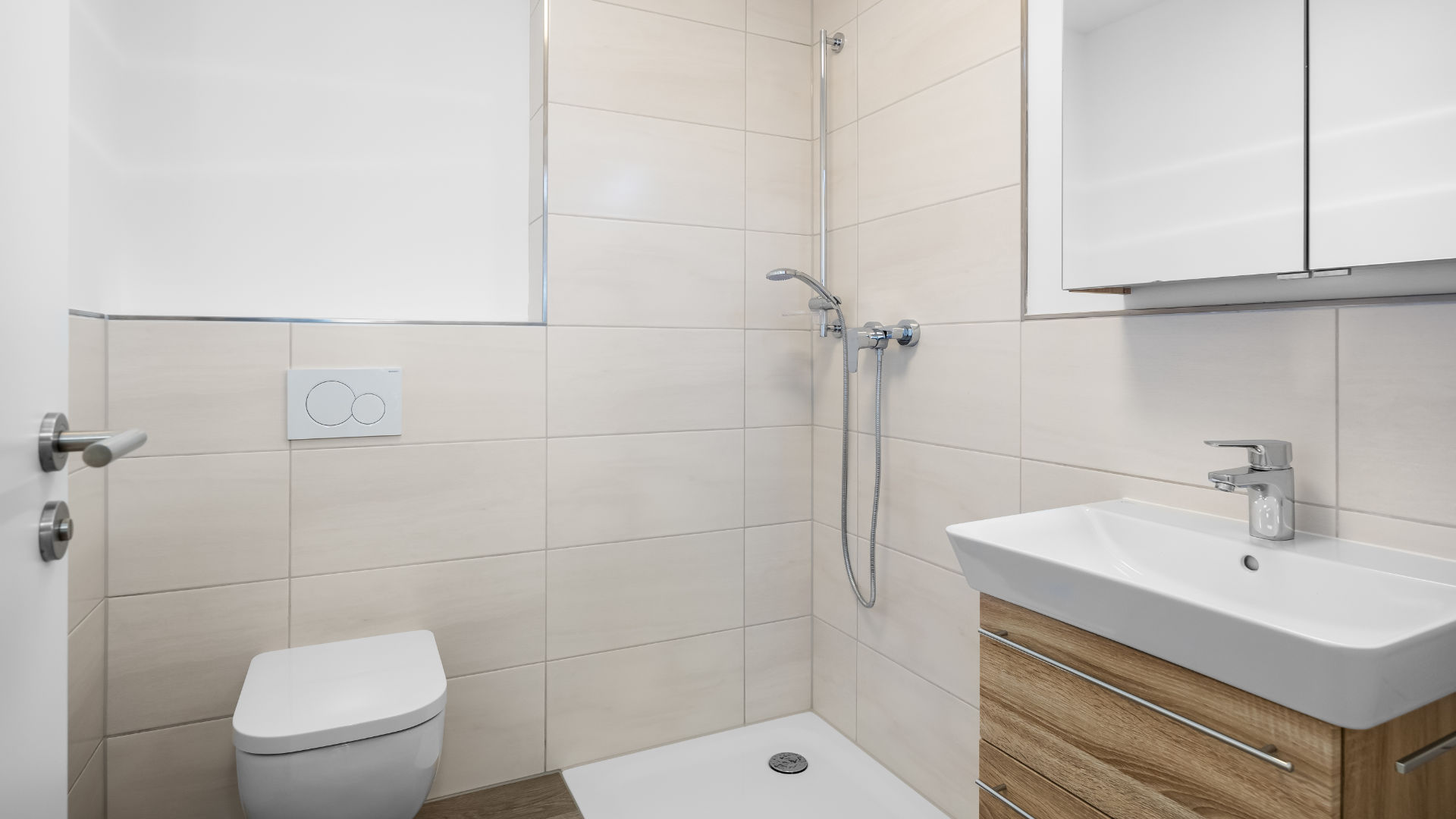 Shower room of the new apartment in Aubing with beige tiles, walk-in shower and washbasin