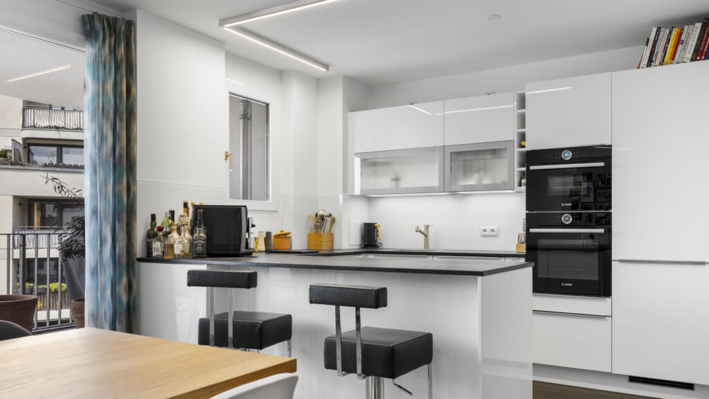Open-plan fitted kitchen with counter and bar stools in a condominium in Munich-Aubing