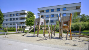 Natural wood play equipment with a slide and climbing net in the sand playground of the Aubing residential complex