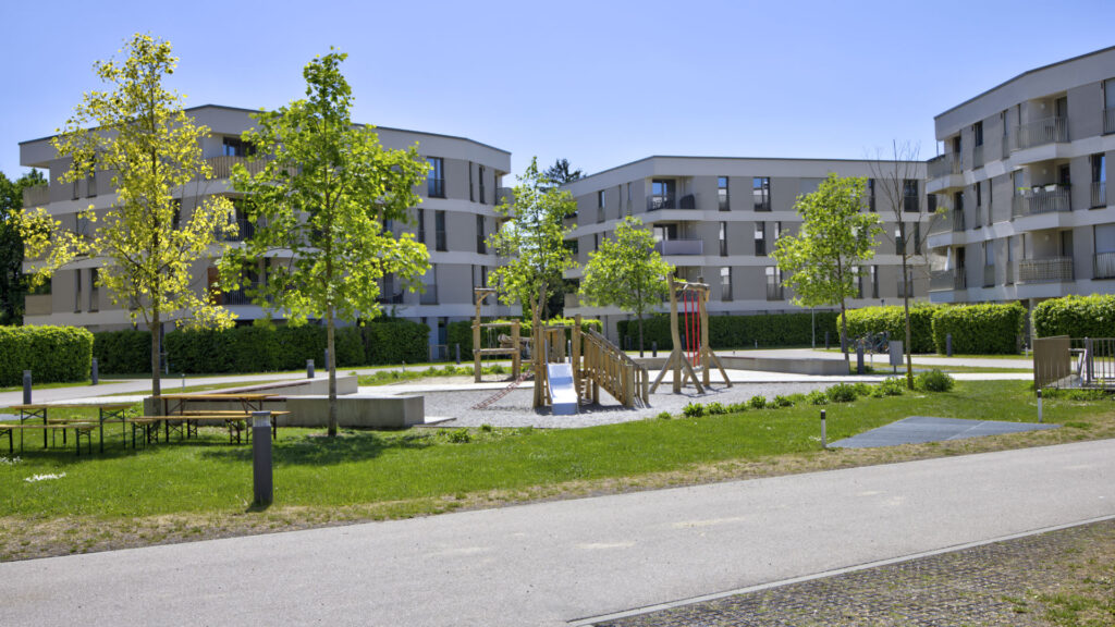 Wooden playground with slide in the courtyard of the Aubing residential complex, surrounded by residential buildings and trees