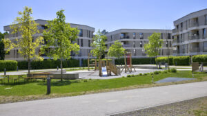 Wooden playground with slide in the courtyard of the Aubing residential complex, surrounded by residential buildings and trees