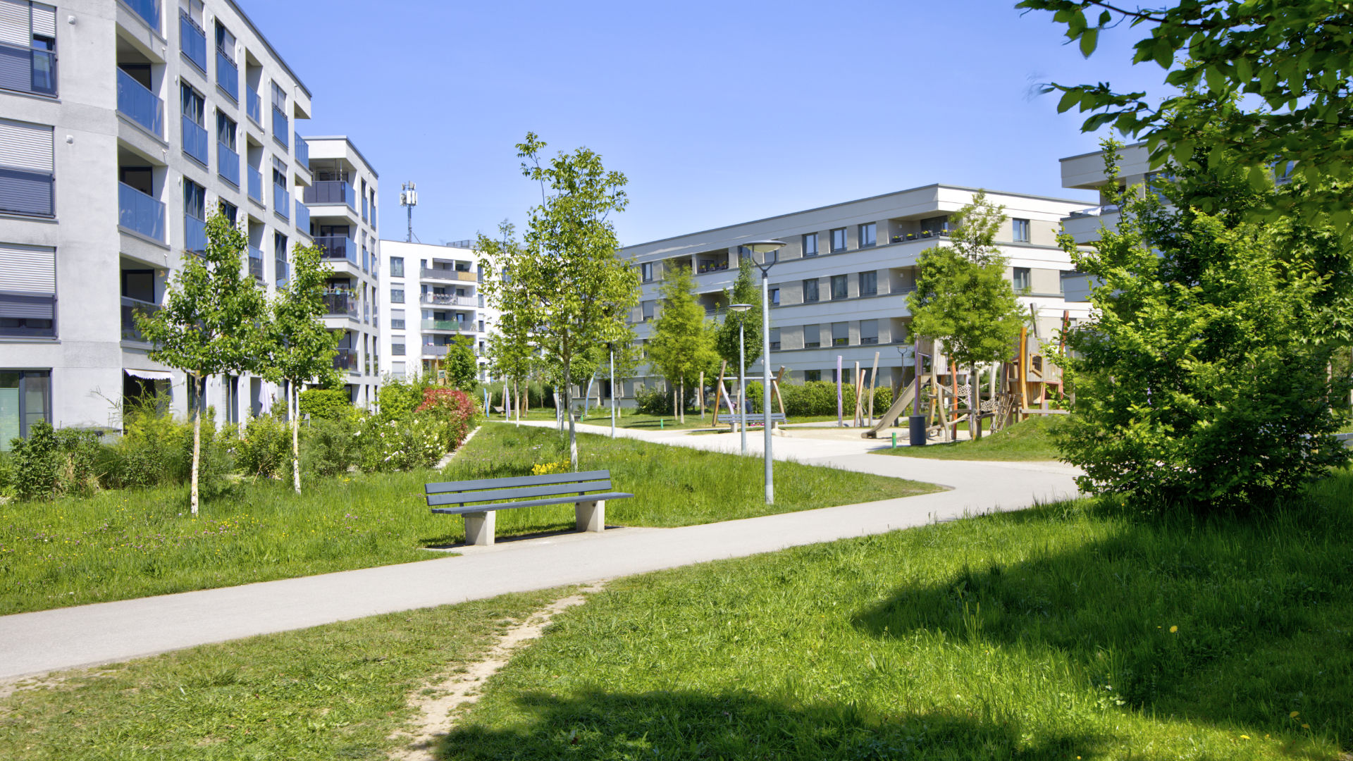 Aubing residential complex with bench, paths, trees, and playground in the background