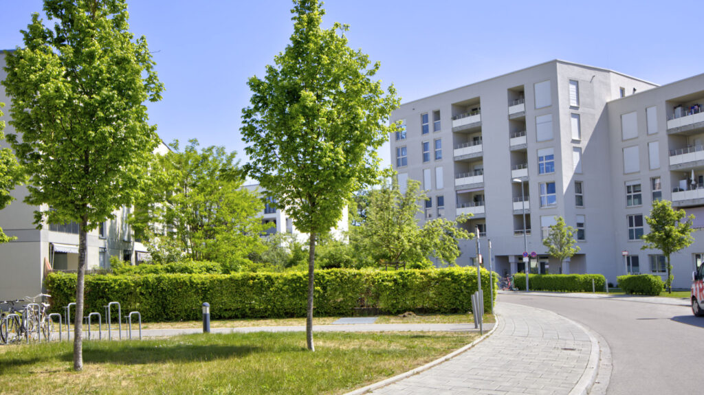 Tree-lined path in front of a modern residential complex in Munich-Aubing