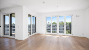 Open-plan living and dining area of the new-build apartment in Aubing with several French doors and parquet flooring