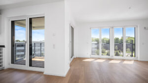 Unfurnished living area of the new Aubing apartment with two balcony accesses and parquet flooring