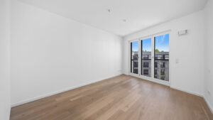 Empty room of the new-build apartment in Aubing with parquet flooring and large balcony door