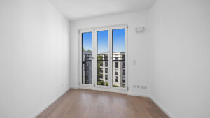 Empty room with balcony door and view of the new development in Munich-Aubing – Rogers Immobilien
