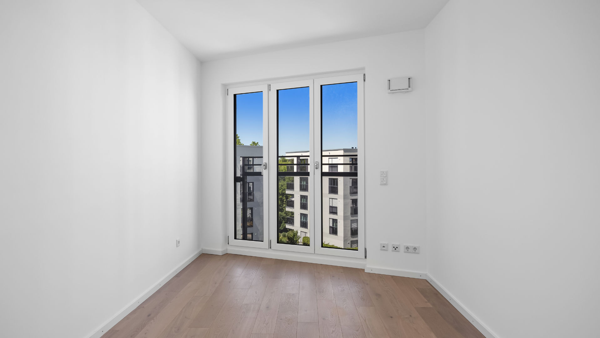 Empty room with balcony door and view of the new development in Munich-Aubing – Rogers Immobilien