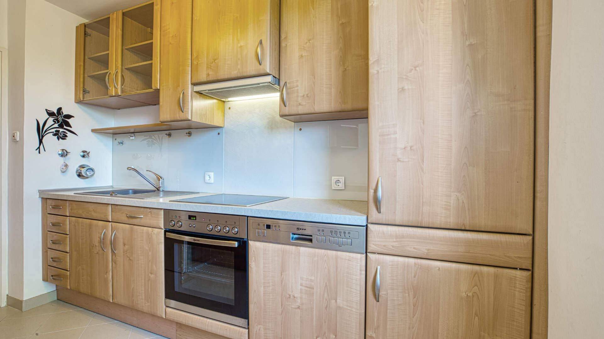 Kitchen in the apartment in Aubing with wooden fronts, built-in stove, cooking surface and decorative wall design