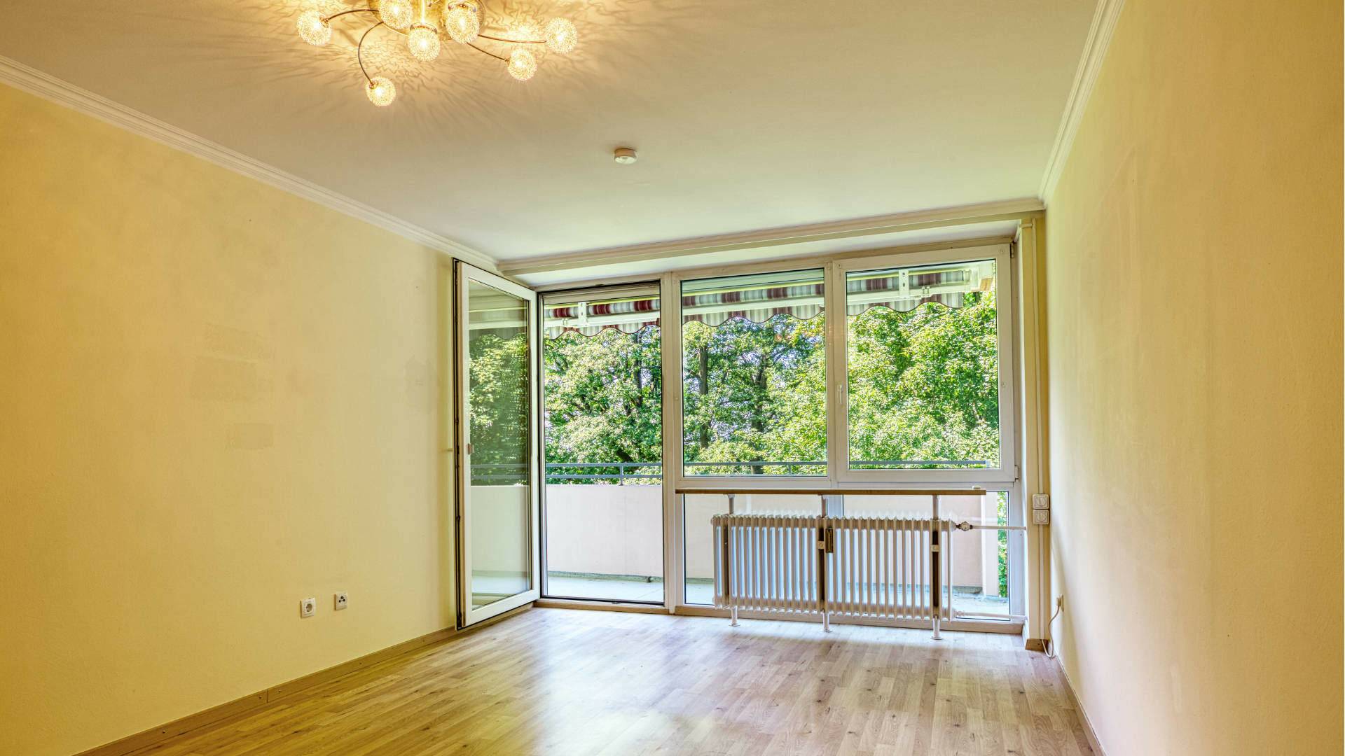 Living room of the apartment in Aubing with ceiling light, balcony door, bright parquet and green views