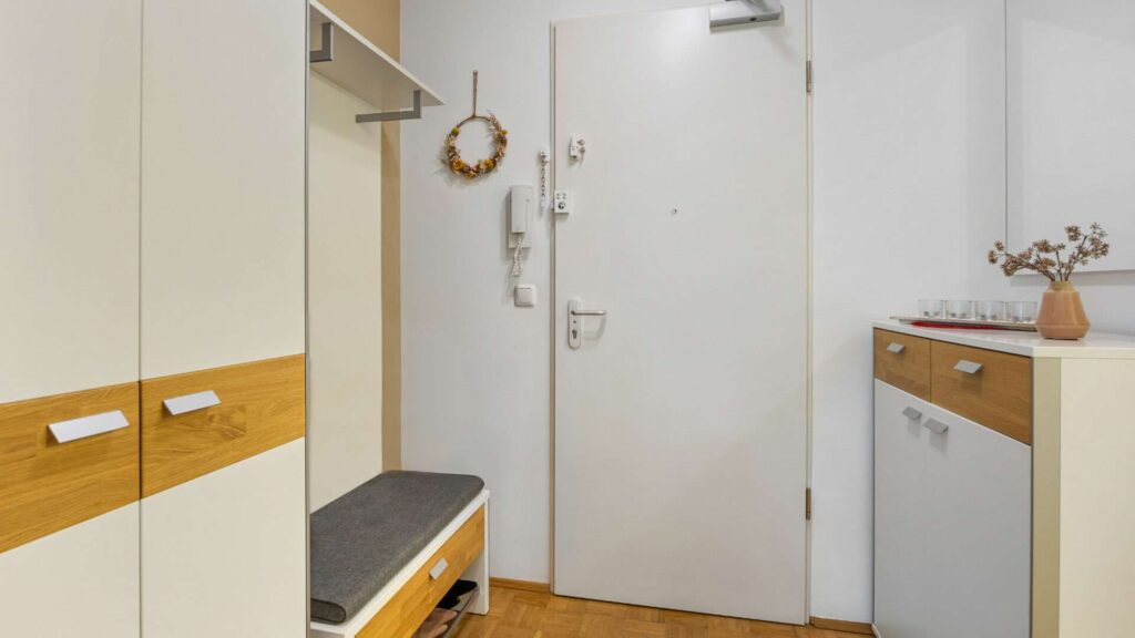 Diele mit weißer Garderobe, Sitzbank und Kommode in Gartenwohnung München-Berg am Laim