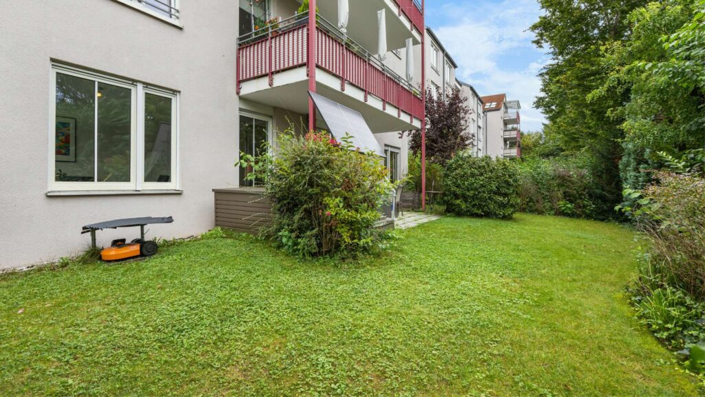 Gepflegter Garten mit Rasenmähroboter und Balkon an Gartenwohnung München-Berg am Laim