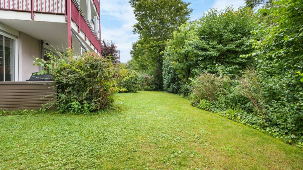 Schmaler Gartenweg mit Rasen und dichter Hecke an der Gartenwohnung München-Berg am Laim