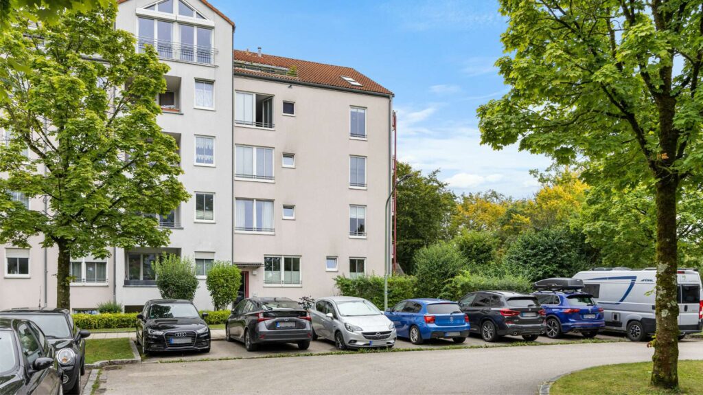 Mehrfamilienhaus mit Stellplätzen und Bäumen in Wohnanlage München-Berg am Laim