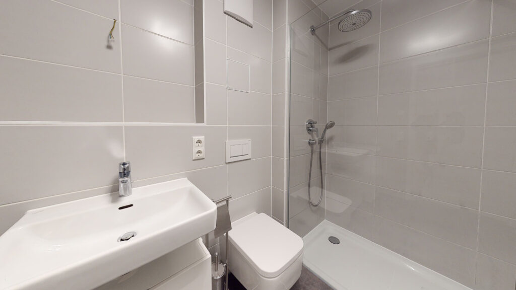 Bathroom with washbasin, toilet, and shower cubicle in an apartment in Munich-Berg am Laim
