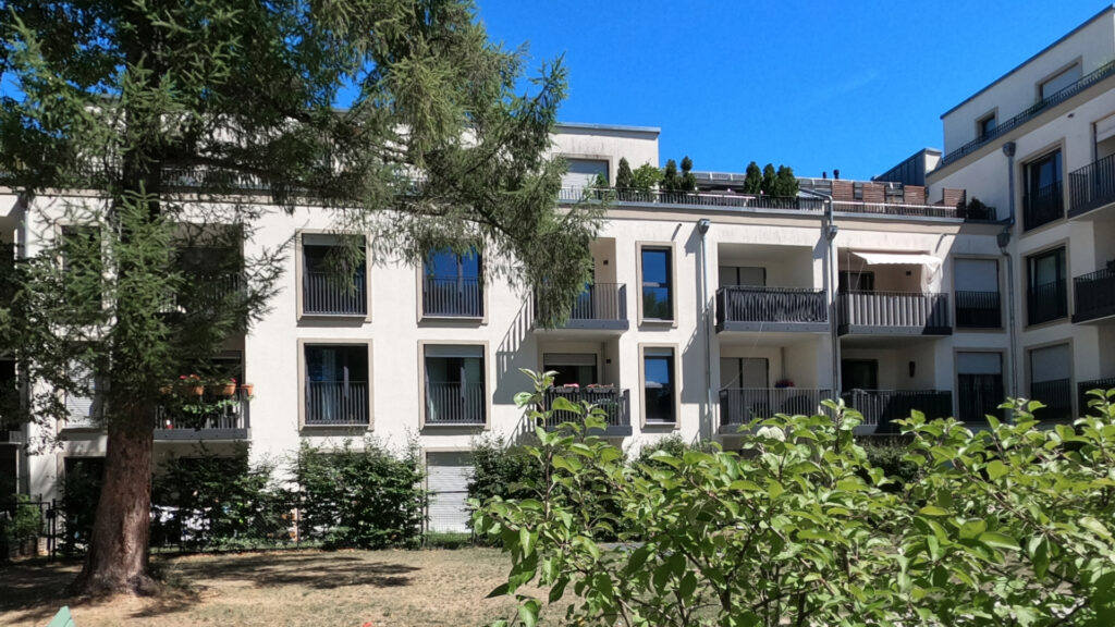 Facade of the residential building with a large tree and glass fronts in Munich-Berg am Laim
