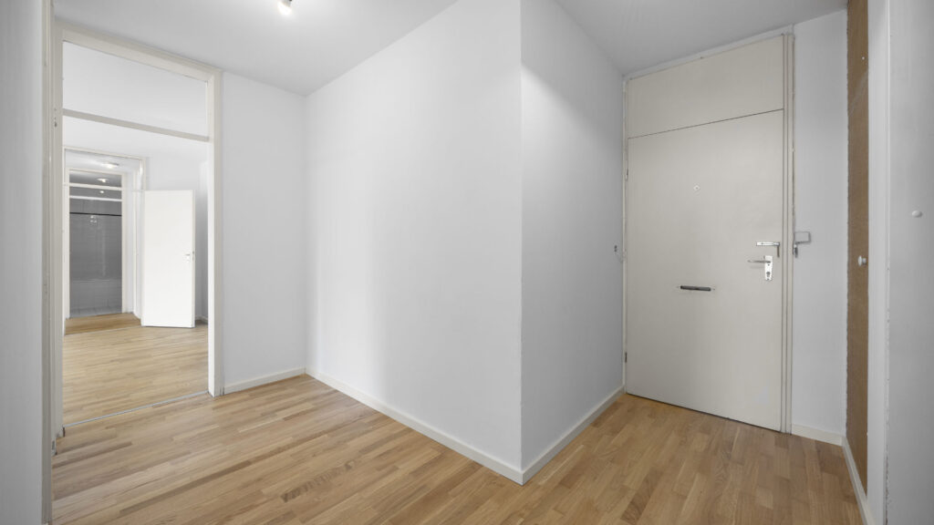 Empty hallway with wooden floor and multiple doors in a condominium in Munich-Berg am Laim