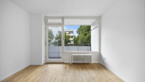 Empty bedroom with floor-to-ceiling windows and a view of neighboring buildings in Berg am Laim