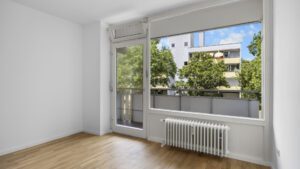 Empty bedroom with balcony door and radiator in condominium in Munich Berg am Laim