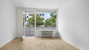 Empty living room with open balcony door and radiator in condominium in Munich Berg am Laim